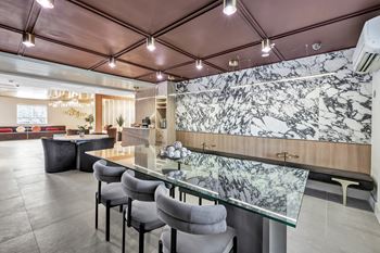 a dining area with a glass table and chairs and a marble wall at The Meriden, Meriden, 06450